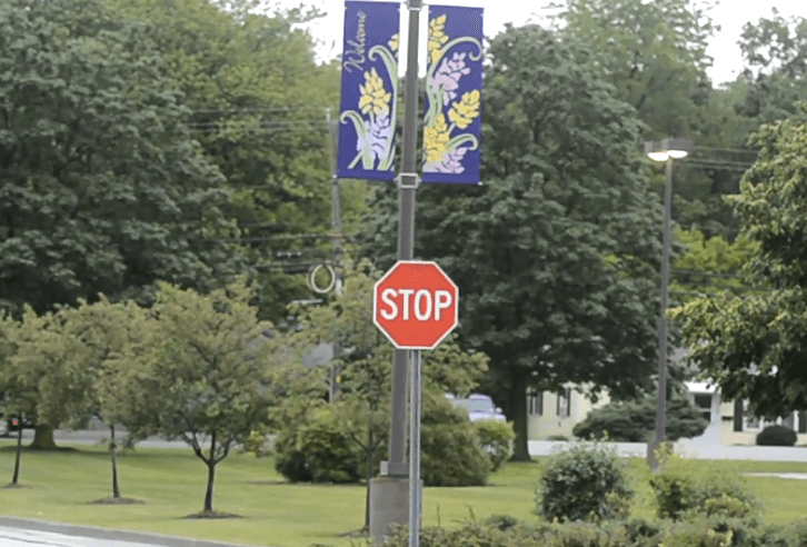 Stop sign, banner, trees in residential area